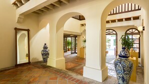 A spacious hallway with arches, tiled flooring, and large decorative vases. - Casa Ritual (Puerto Vallarta)