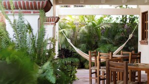 A covered patio area with a dining table and chairs, surrounded by lush greenery and a hammock. - Casa Ritual (Puerto Vallarta)