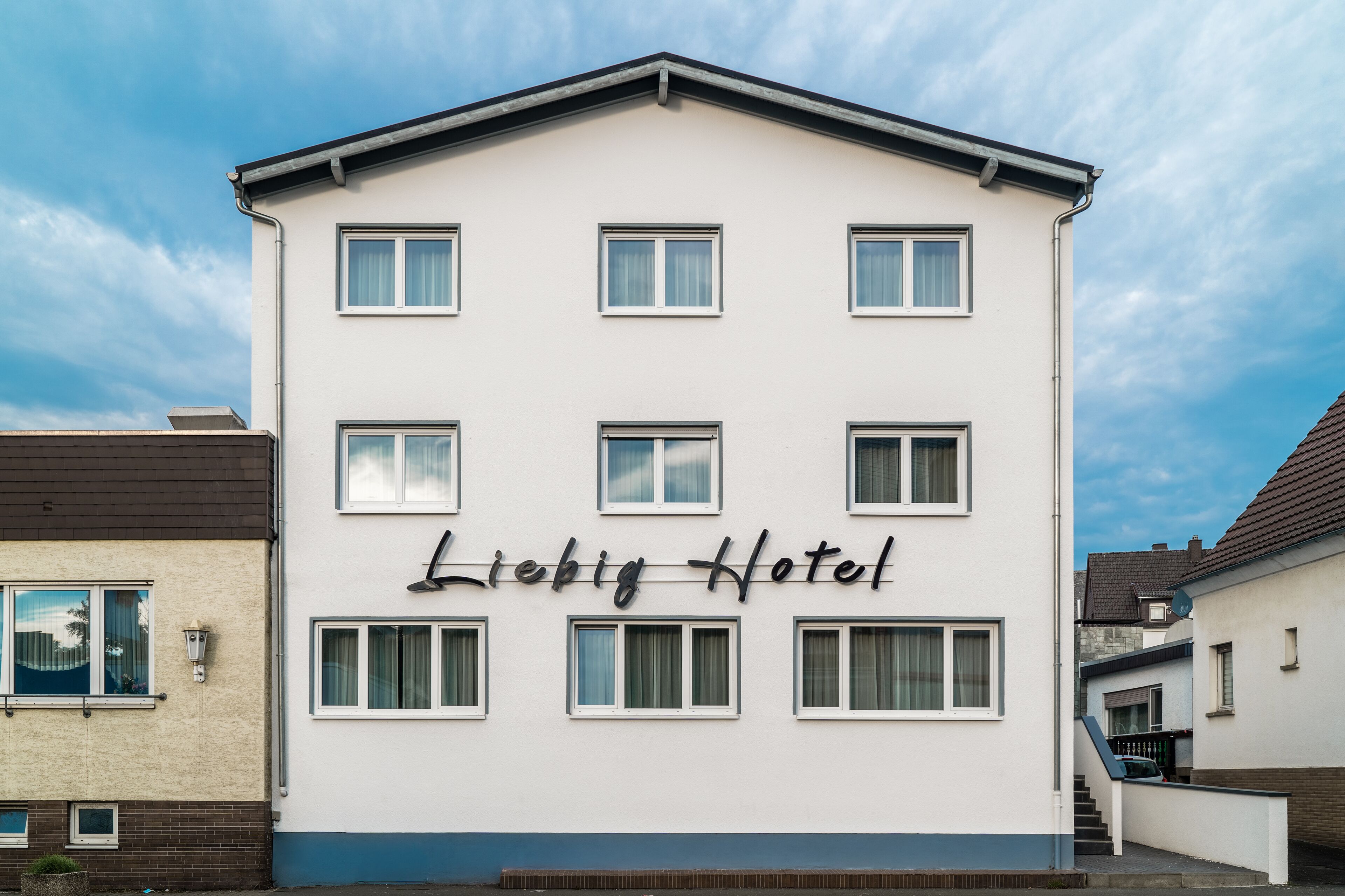 A building with the sign 'Liebig Hotel' on the facade, featuring a symmetrical window arrangement and a flat roof.