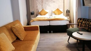 Una habitación de hotel moderna con sofá, una mesita y una cama con cabecero.