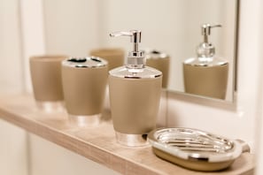 Bathroom features a sleek vanity with a soap dispenser and matching soap dish.