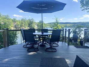 Une terrasse avec une table et des chaises, donnant sur un plan d’eau.