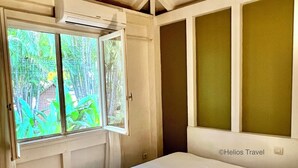 A bedroom with a bed, a window with a view of greenery, and a ceiling fan. - Villa Mabouya (6 pers.) (Deshaies)