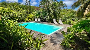 A swimming pool surrounded by lush greenery and two lounge chairs. - Villa Mabouya (6 pers.) (Deshaies)
