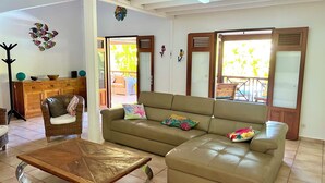 Una sala de estar con sofá, una mesa de centro, un mueble de madera y un ventilador de techo.