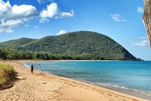 A beach with a mountain in the background and a clear sky.