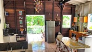A cozy living area with a sofa, a TV, and a bookshelf. There's a kitchen with a fridge, stove, and dining table.