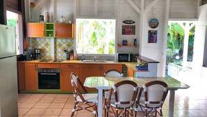 A kitchen with a dining area, featuring a refrigerator, a coffee maker, a microwave, and a tiled backsplash.