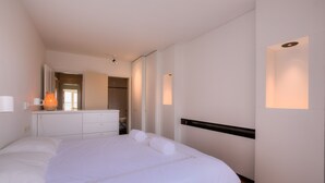 Una camera d'albergo moderna con un letto grande, una cassettiera, uno specchio e un armadio a muro.