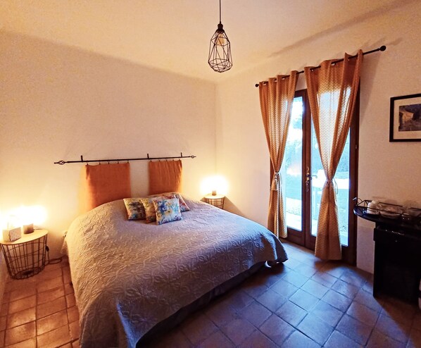 A bedroom with a bed, two bedside lamps, a window with curtains, and a hanging light fixture. - Suite with private garden Aix-Luberon-Verdon * Dinner and Jacuzzi extra (Peyrolles-en-Provence)