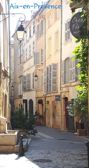 A narrow street with buildings featuring shuttered windows and a sign for 'Chez Firmin' restaurant. - Suite with private garden Aix-Luberon-Verdon * Dinner and Jacuzzi extra (Peyrolles-en-Provence)