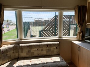 A room with a large window, a cushioned bench, and a TV on a wooden cabinet.
