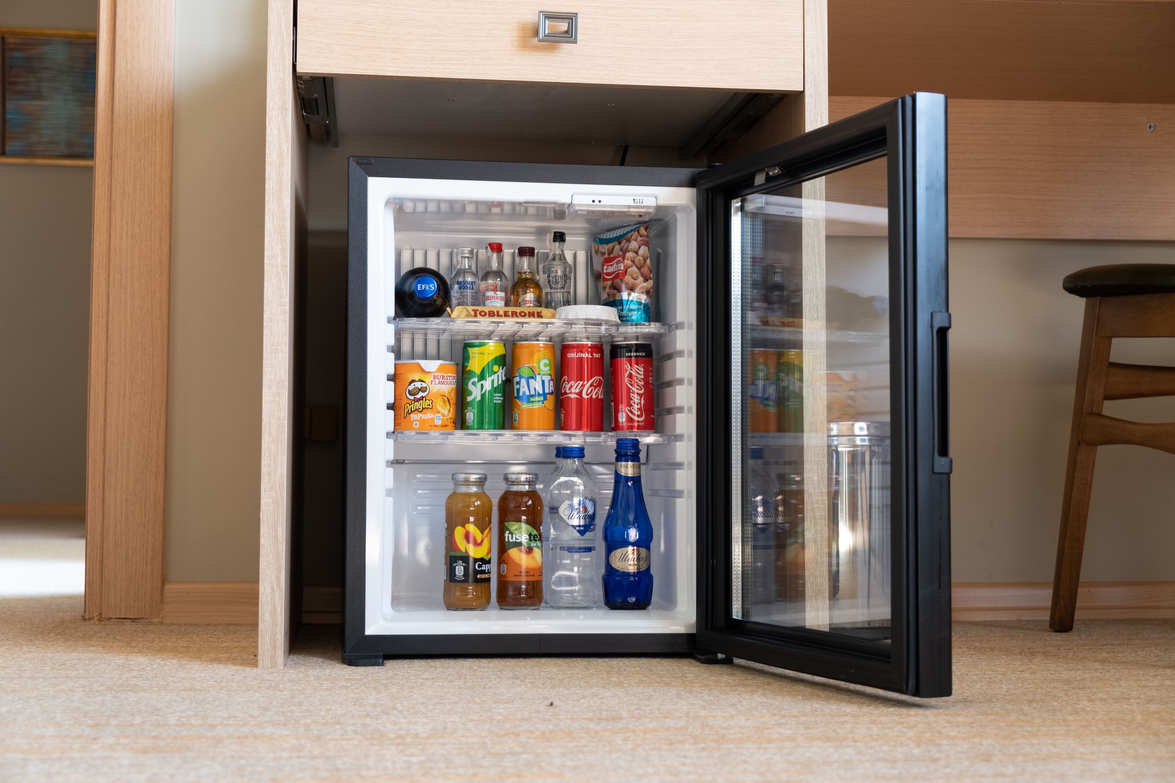 A refrigerator stocked with various beverages and snacks, including sodas, juices, and bottles.