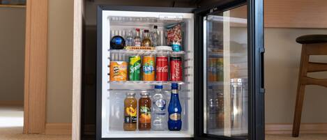 A refrigerator stocked with various beverages and snacks, including sodas, juices, and bottles.