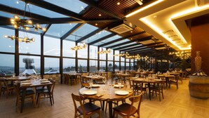 Un restaurante espacioso con techos altos, ventanas amplias y numerosas mesas de comedor.