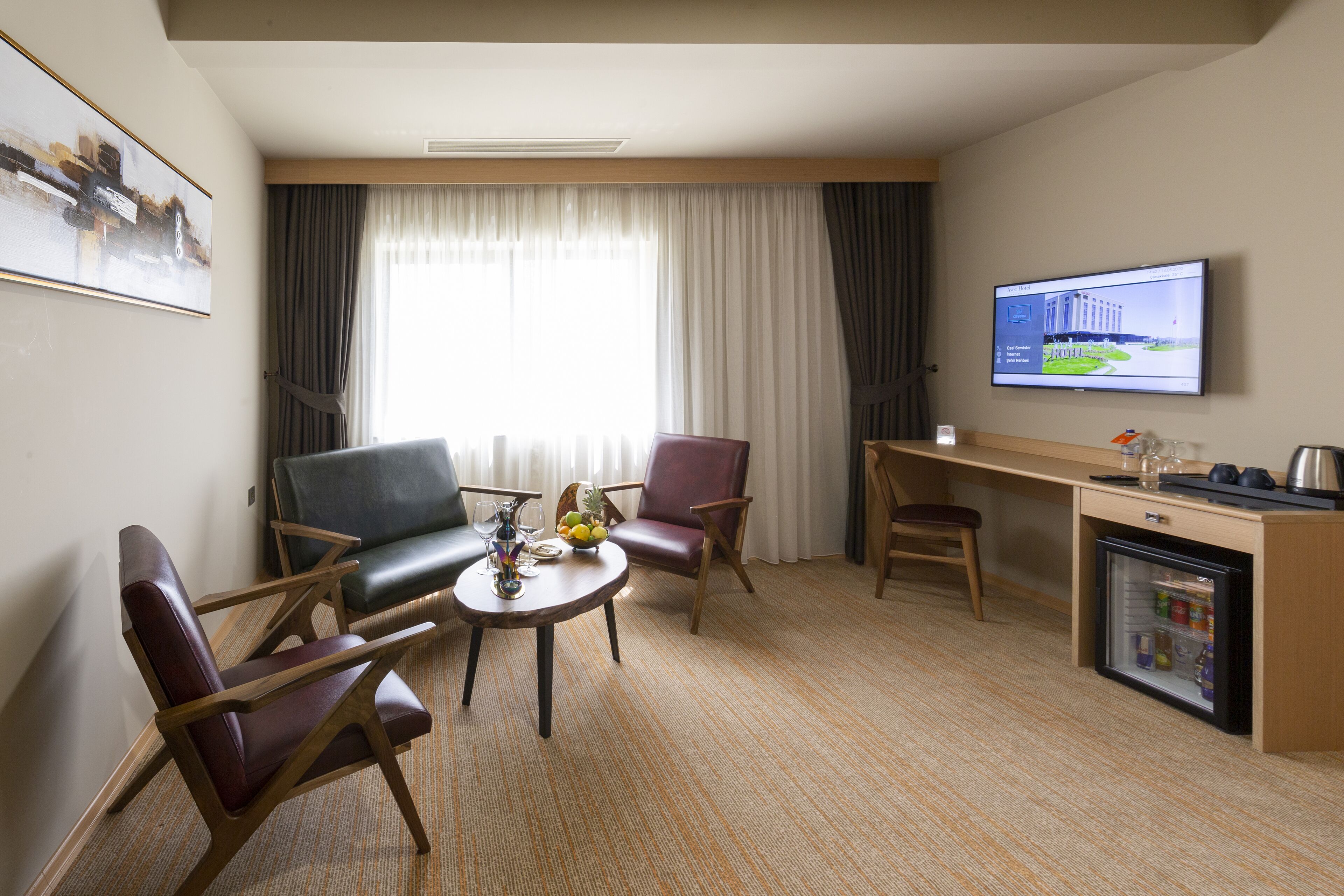 Une chambre d’hôtel équipée d’un coin salon, d’un bureau, d’une télévision et d’un mini-réfrigérateur.