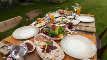 Mesa exterior dispuesta con diversos alimentos, copas de vino y una vista panorámica de fondo.