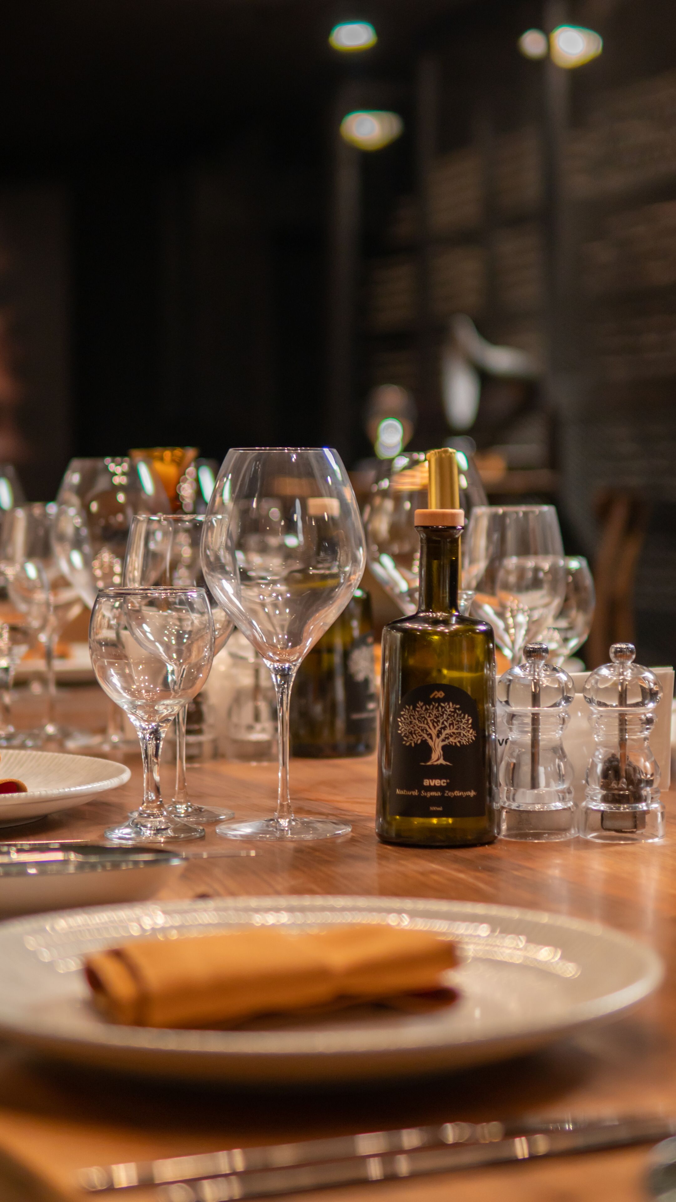 Una mesa servida con copas de vino, una botella de vino y saleros y pimenteros.