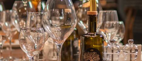 Una mesa servida con copas de vino, una botella de vino y saleros y pimenteros.