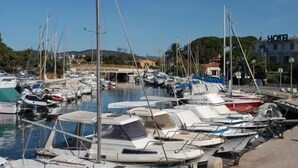 A marina with multiple boats docked, a clear sky, and a building with "HOTEL" signage in the background. - 3 bedroom house 90m² Hyères the sea is 50 meters from the beach (Hyères)