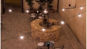 A circular stone structure with a central pillar, surrounded by tables and chairs. - Relais Convento Santa Croce (Sant'Anatolia di Narco)