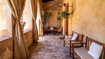 A stone-floored patio with wooden benches and a hanging plant.