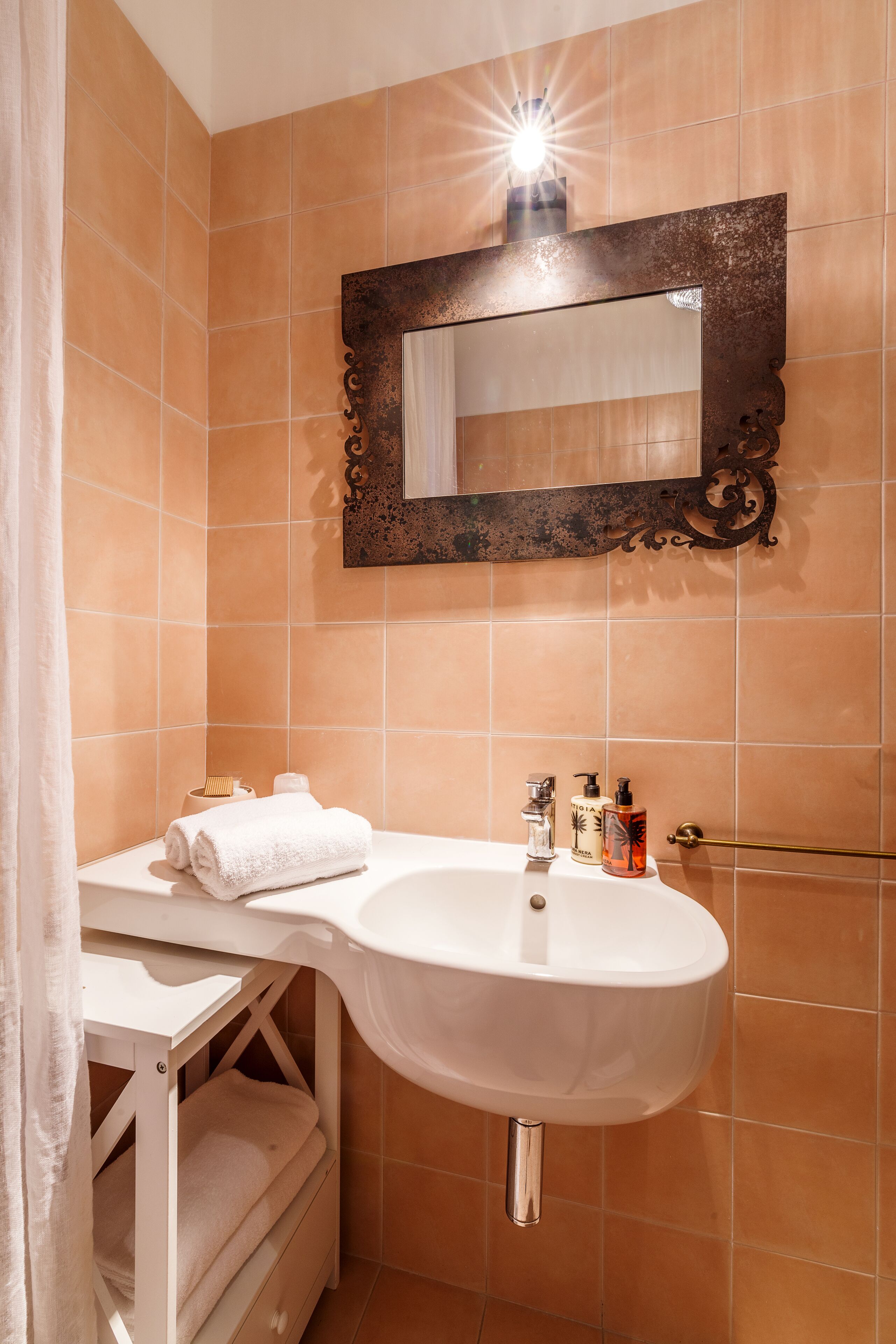 A bathroom with a white sink, a mirror with an ornate frame, and a towel rack.