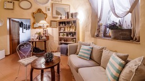 A cozy living room with a sofa, a coffee table, and a bookshelf filled with books and decorative items. - Relais Convento Santa Croce (Sant'Anatolia di Narco)