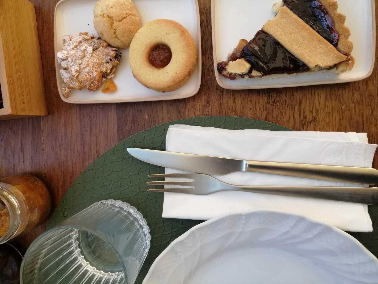 Una mesa de comedor con un plato de comida, un vaso y cubiertos.
