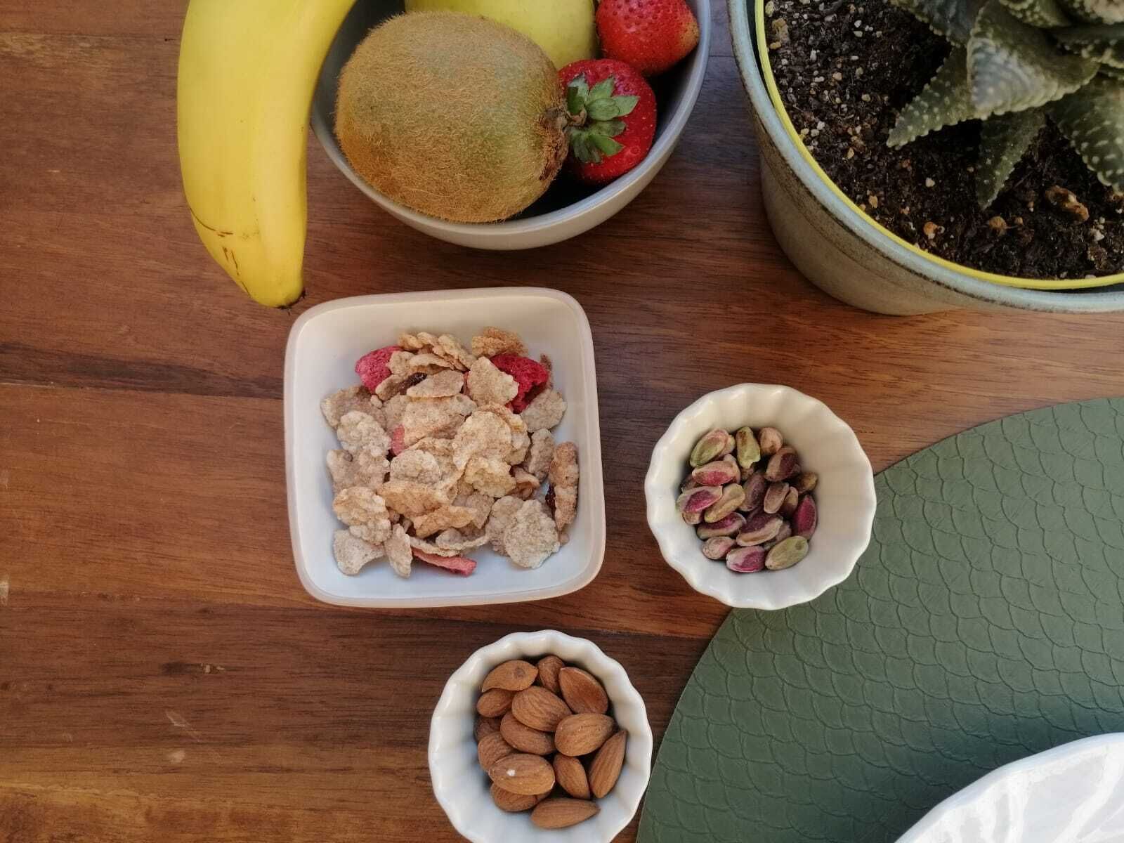 Une table en bois sur laquelle se trouvent des bols contenant divers types de noix, des fruits secs et un bol de céréales.