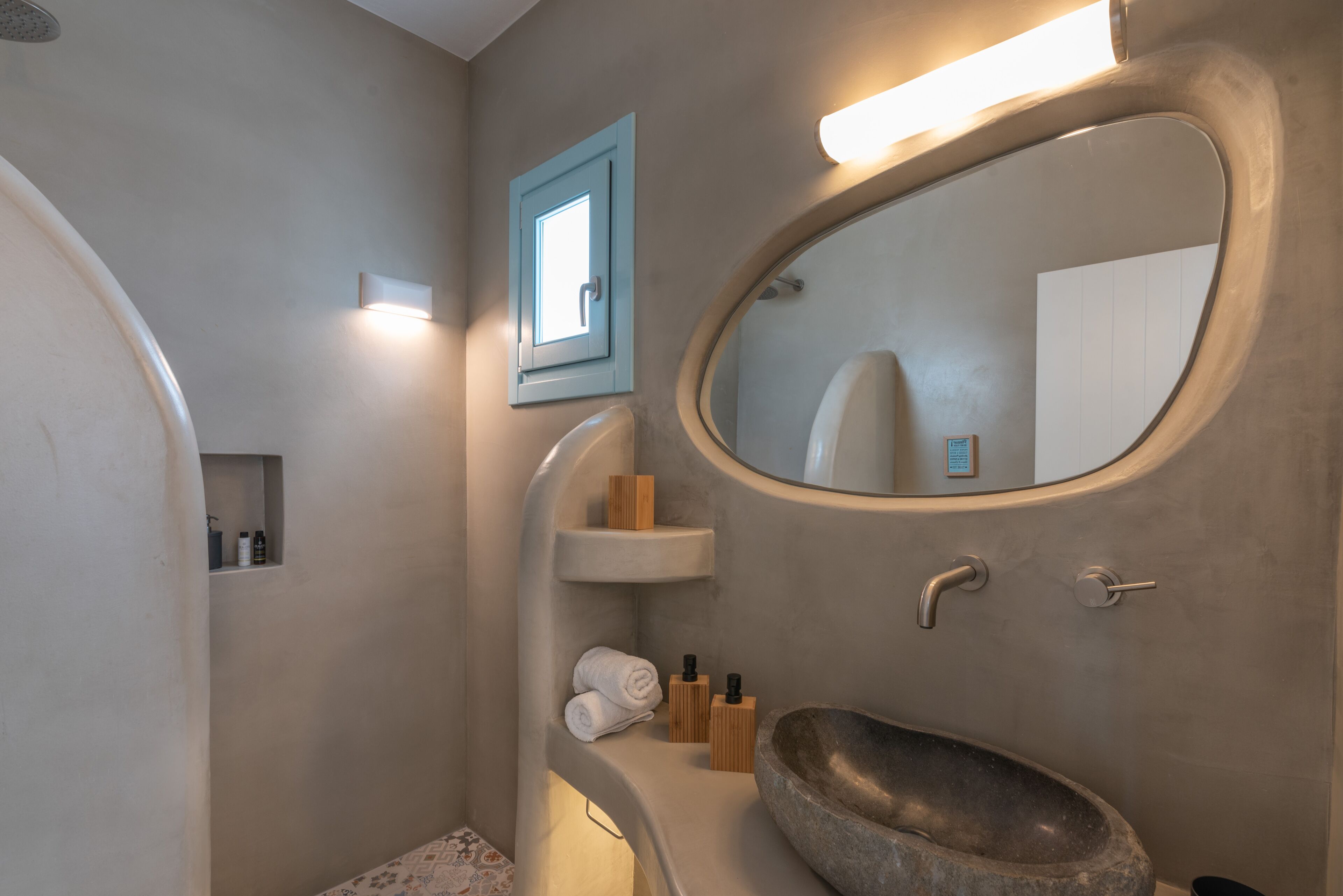 A bathroom with a stone sink, a mirror, and a towel rack.