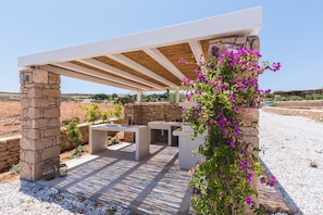 An outdoor patio with stone pillars, a wooden pergola, and a table.