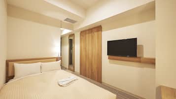 Quarto de hotel com uma cama, televisão fixada na parede e guarda-roupa de madeira.