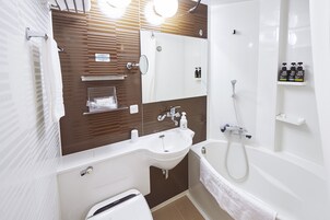 Une salle de bain moderne avec un lavabo blanc, un miroir et une baignoire. On y trouve des articles de toilette sur une étagère et un porte-serviettes.