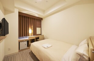 A hotel room with a bed, a desk, a television, and a mirror.