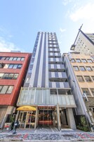 Un hotel moderno con un ingresso ben visibile, ampie vetrate e un ristorante chiamato "Pasta Palace" al piano terra.