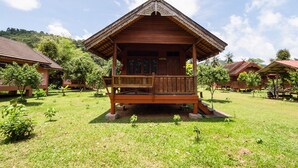 A wooden pavilion with a balcony, surrounded by lush greenery and other similar structures.