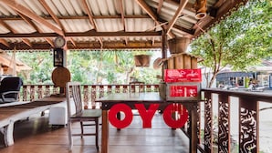 A covered outdoor seating area with a table displaying the word "OYO" in large letters, surrounded by wooden furniture and a decorative railing.