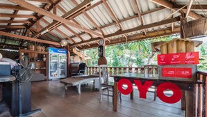 A covered outdoor area with a wooden table, chairs, a refrigerator, and a Panasonic display.