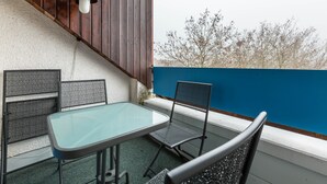 Uma varanda com mesa e cadeiras, um abajur e vista para as árvores.