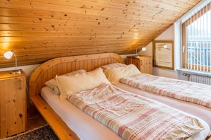 Une chambre avec deux lits, un plafond en bois et une fenêtre donnant sur un beau paysage.