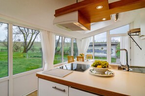A kitchen with a large window, a bowl of fruit, and a view of a green landscape. - Light-Flooded Holiday Apartment “Haus Nussbaum” close to Lake Constance with Wi-Fi, Terrace & Garden; Parking Available (Überlingen-Hödingen)