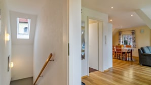 Ein modernes Interieur mit einer Treppe, einem Essbereich mit Tisch und Stühlen sowie einer Couch.