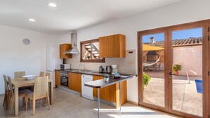 A modern kitchen with wooden cabinets, a dining table with chairs, and a sliding glass door leading to an outdoor area with a pool.