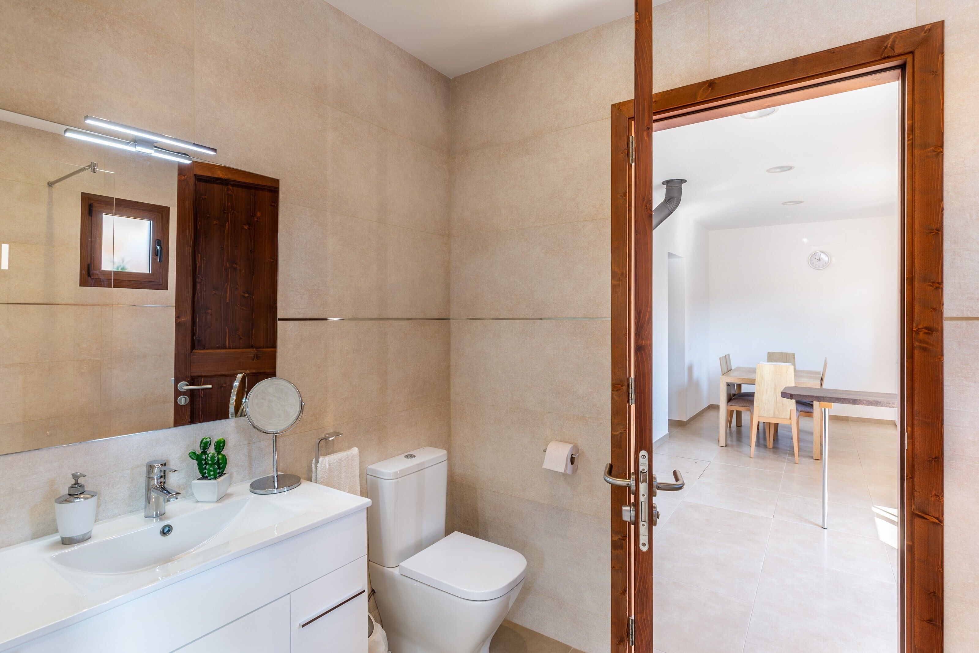 A bathroom with a sink, mirror, toilet, and shower.