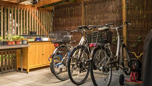 Uma cerca de madeira, um painel de bambu e um suporte para bicicletas com duas bicicletas.
