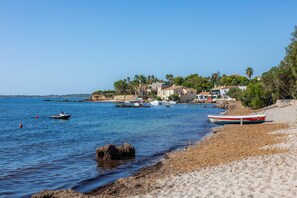 A beach with boats, a sandy shore, and buildings in the background.