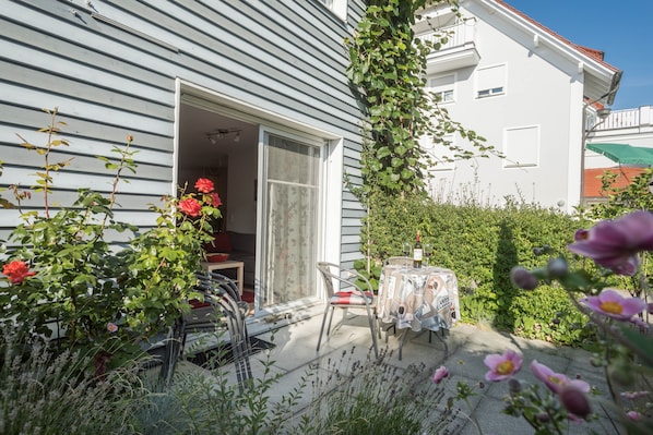 A house with a patio, a table with a tablecloth, and a chair.