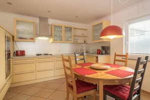 A kitchen with wooden cabinets, a dining table with chairs, and a red pendant light.