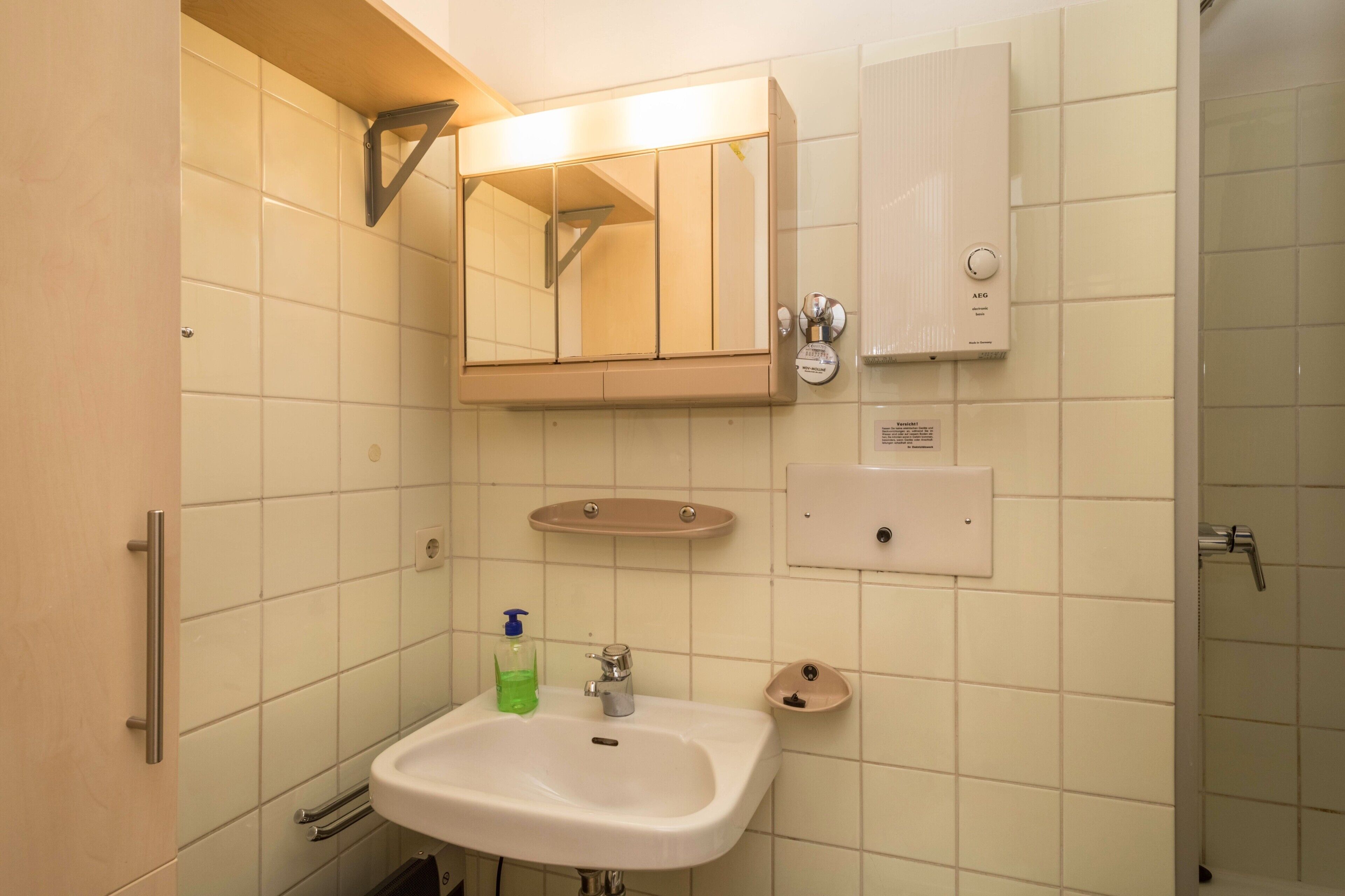 Casa de banho com lavatório, espelho, porta-toalhas e aquecedor na parede.